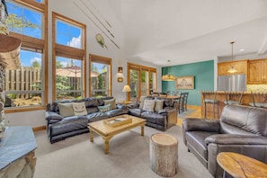 A spacious living room with leather sofas, a wooden coffee table, and a dining area with a kitchen counter.