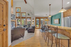Une cuisine spacieuse avec des meubles en bois, un coin bar et de grandes fenêtres.