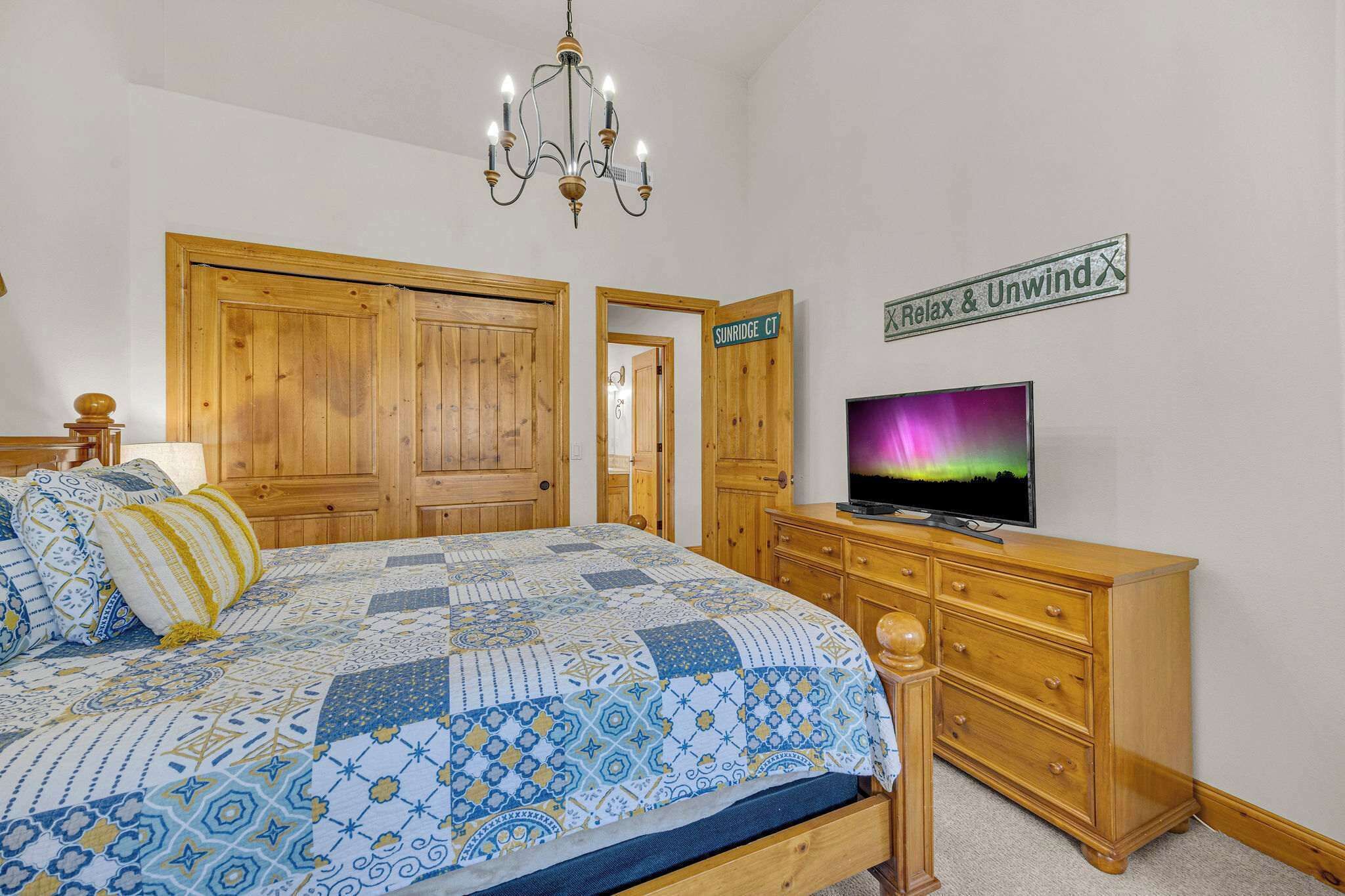 Une chambre à coucher avec un grand lit, une armoire en bois, un téléviseur et une pancarte indiquant « Sunridge CT ».