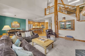 A spacious living room with leather sofas, a wooden coffee table, and a staircase leading to an upper level.