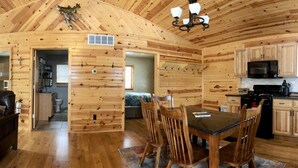 Interior acogedor de una cabaña con sala de estar, comedor y cocina, destacando paredes y pisos de madera.