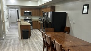 Eine moderne Küche mit Holzschränken, einem Edelstahlkühlschrank und einem Essbereich mit Holztisch und Stühlen.