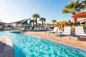 A swimming pool with lounge chairs and umbrellas, surrounded by palm trees and buildings. - Poolside Villa | Private Hot Tub | Sleeps 20 | Arcadia #2 (Santa Clara)