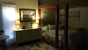 Una camera da letto con un letto a castello, una scrivania con una lampada, una sedia e un quadro appeso al muro.
