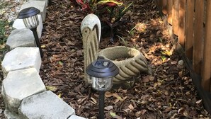 Un giardino con un cordolo in pietra, un vaso decorativo in pietra e un recinto in legno.