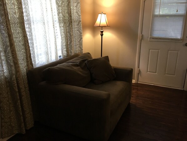A living room with a sofa, a lamp, and a door.