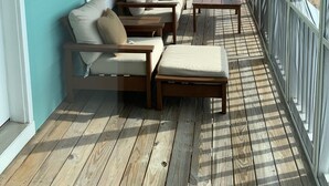 En inglasad veranda med trägolv, en beige soffgrupp och ett träbord.