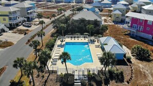 Ett bostadsområde med hus, en swimmingpool och utsikt över havet.