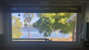 A kitchen with a window overlooking a lake and trees. - Lakehouse Retreat with dock, paddle boat, canoe & kayaks! Now have Gas Grill  (Anderson)
