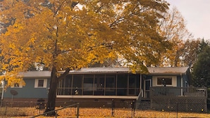 A building with large windows and a balcony, surrounded by trees with yellow leaves. - Lakehouse Retreat with dock, paddle boat, canoe & kayaks! Now have Gas Grill  (Anderson)