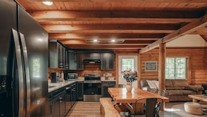 L’intérieur d’une cabane comprenant une cuisine, un coin repas et un salon.