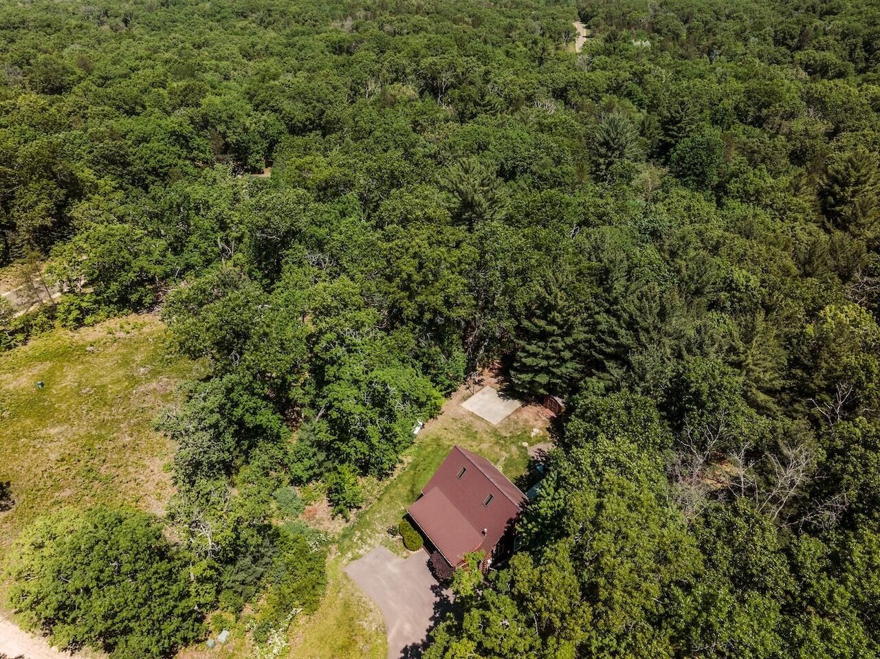 An aerial view of a house surrounded by dense forest.