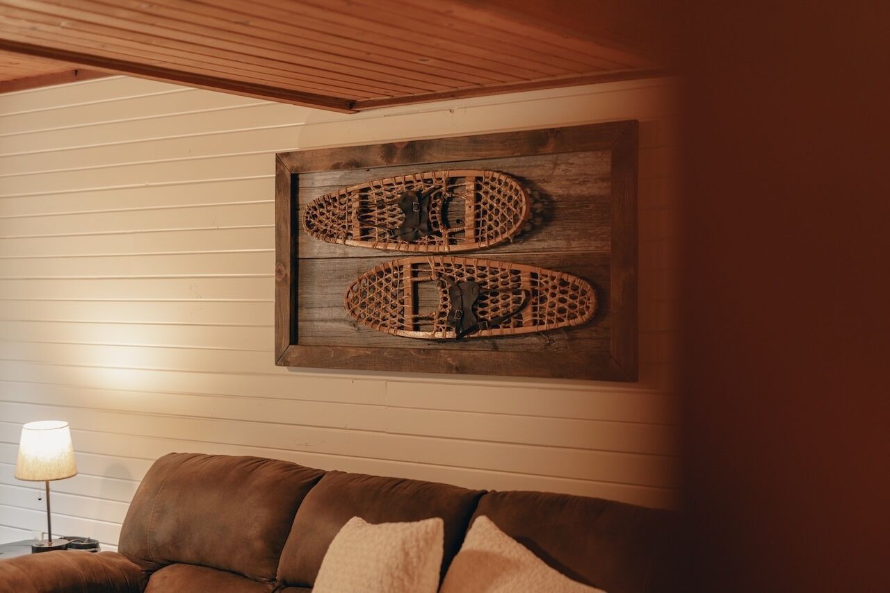 Una habitación con techo de madera, un sofá de cuero marrón y una obra de arte de madera colgada en la pared.