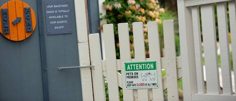 A gated entrance with a sign indicating the backyard is available to guests.