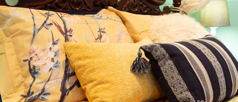 A bed with floral and striped pillows, a fluffy white pillow, and a wooden headboard.