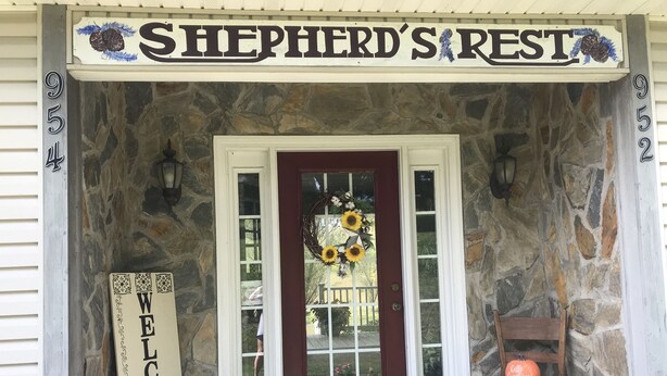 A stone house entrance with a red door, a 'Welcome' sign, and a 'Shepherd's Rest' sign above. - June’s Place In The Country  (Galax)