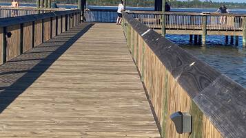 Un muelle de madera que conduce a una estructura con techo metálico y un ventanal triangular.