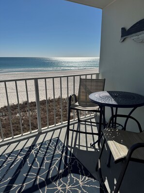 Un balcon avec vue sur la plage, une table et des chaises.