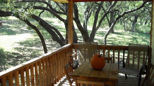 A wooden deck with a table and chairs, a ceiling fan, and a view of a wooded area. - One and a half miles from the Frio River! The stars at night are big and bright! (Leakey)