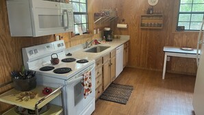 A compact kitchen with a microwave, stove, sink, and wooden cabinets. - One and a half miles from the Frio River! The stars at night are big and bright! (Leakey)