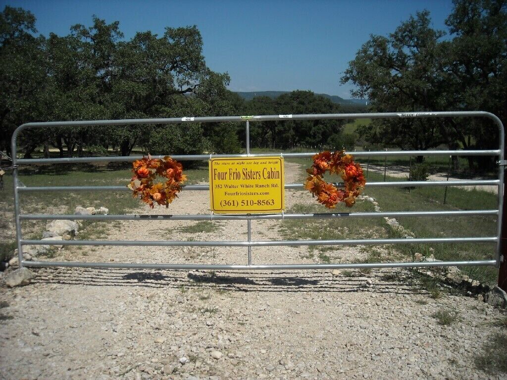 A gated area with a sign for the Four Frio Sisters Cabin, including an address and phone number.