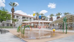 Ein Außenpoolbereich mit Wasserrutsche, Palmen und einer überdachten Sitzgelegenheit.