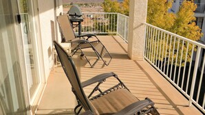 Ein Balkon mit zwei Liegestühlen und einem Tisch, der einen schönen Blick auf Hügel und Bäume bietet.