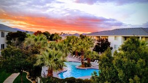 Ein Resort mit Swimmingpool, umgeben von Palmen und einem Sonnenuntergangshimmel.