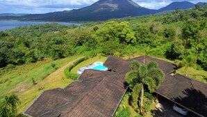 Een tropisch resort met een zwembad, weelderige begroeiing en een berg op de achtergrond.
