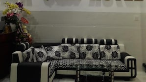 A reception area with a sofa, a wall clock, and a sign that reads "QUAN QUAN HOTEL". - Anh Quan Hotel (Quy Nhon Nam)