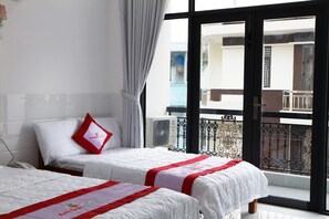 A hotel room with two beds, a balcony with a view, and a window with curtains. - Anh Quan Hotel (Quy Nhon Nam)