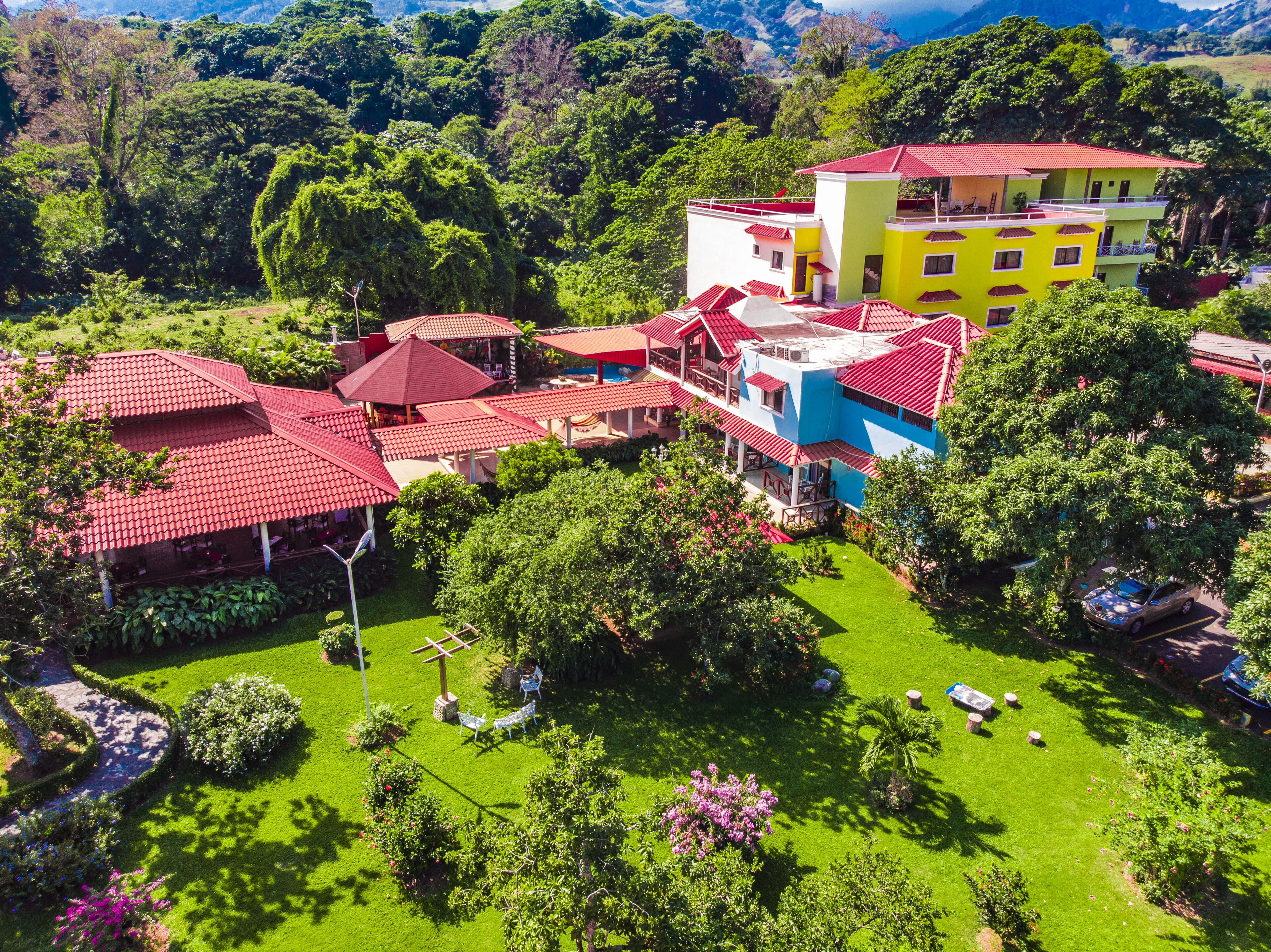 A multi-story building with red-tiled roofs, surrounded by lush greenery and a well-maintained lawn.