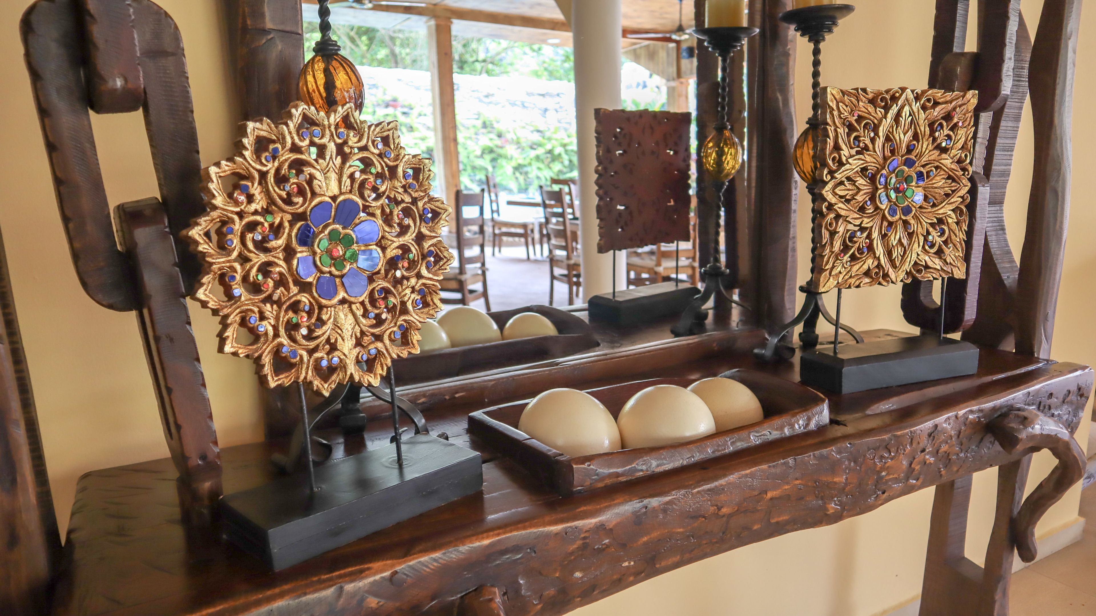 A wooden tray with decorative items and a mirror reflecting a room with chairs and a table.