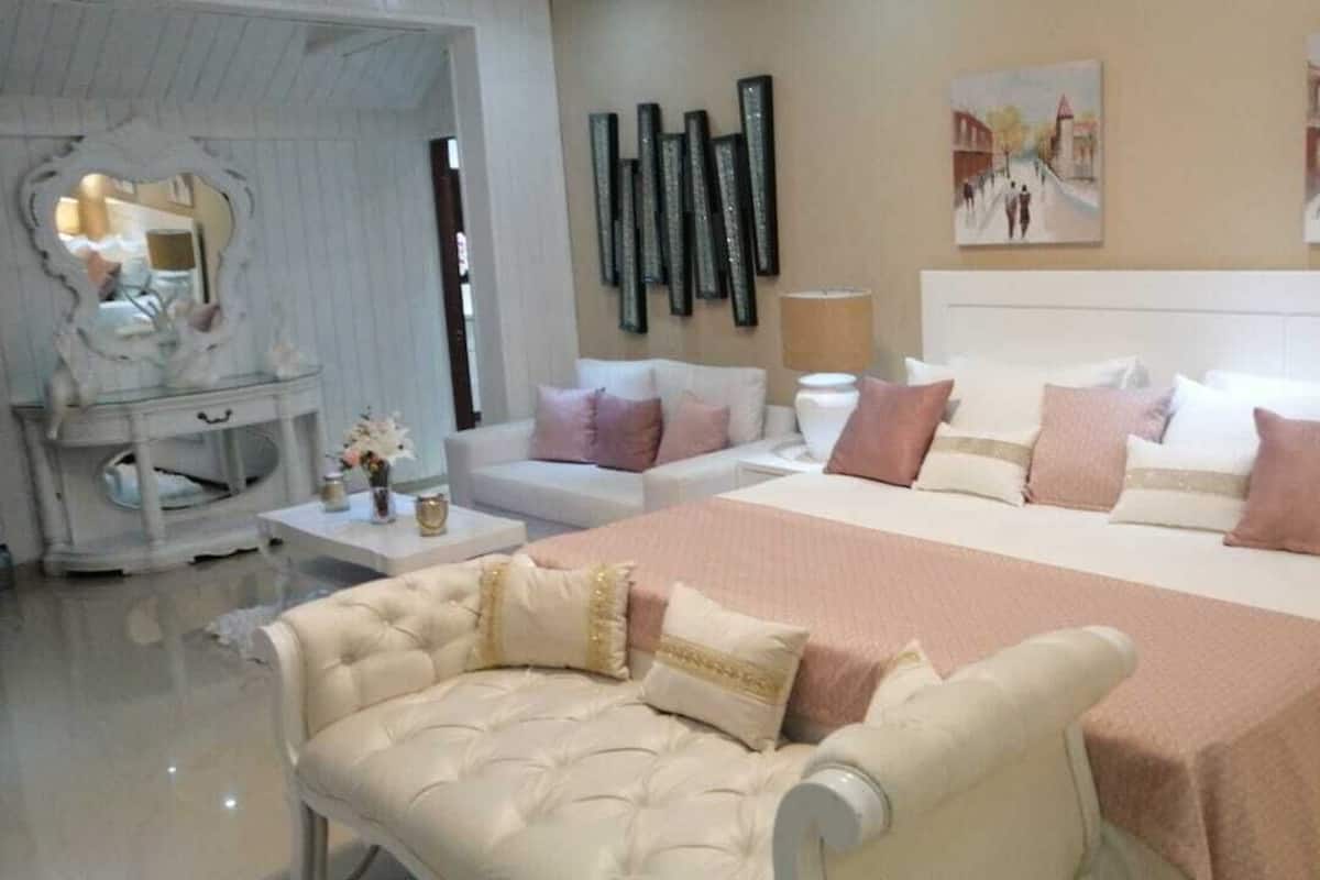 A bedroom with a large bed, two bedside tables, a chair, and a mirror.