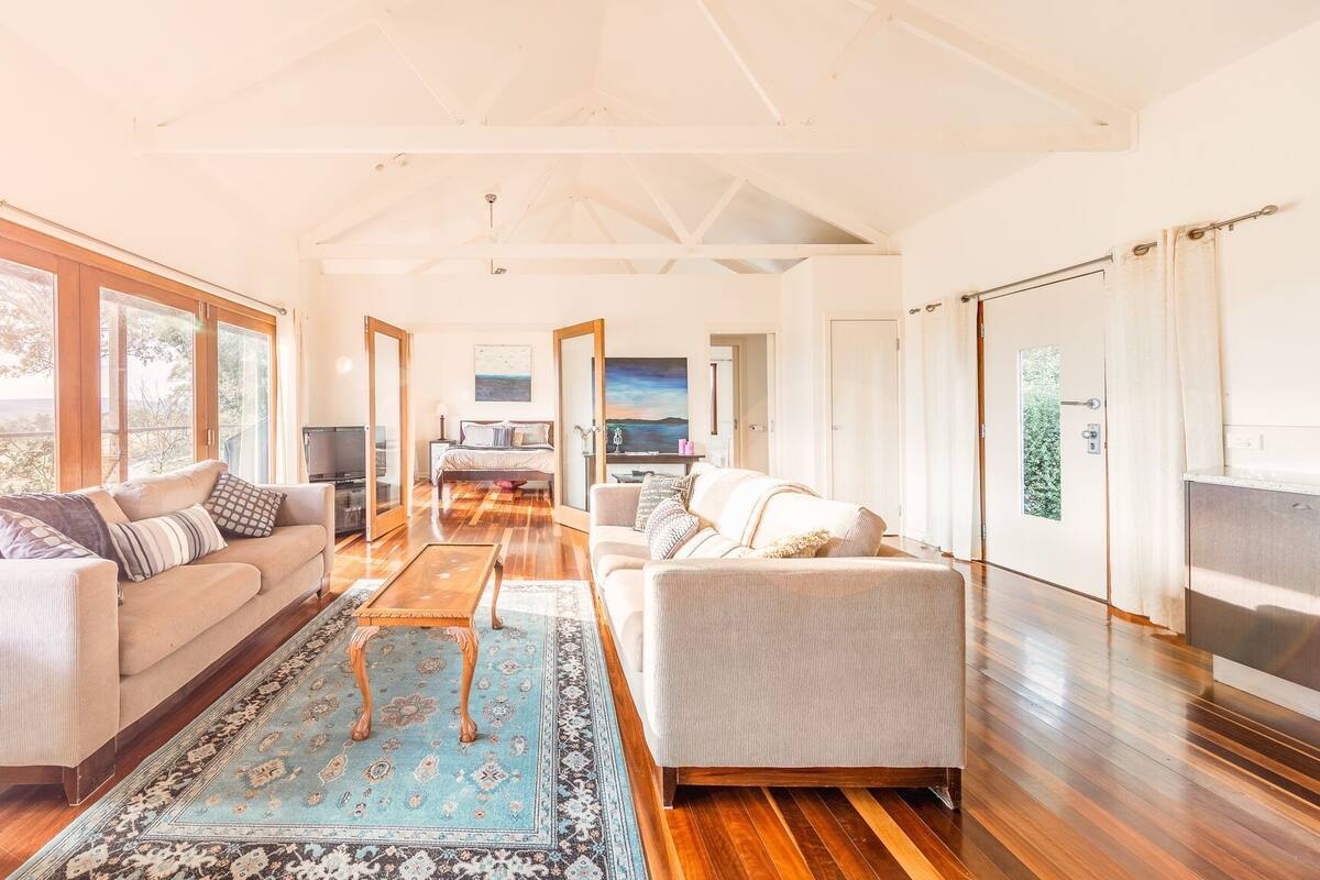 A spacious living room with a large window, a sofa, a coffee table, and a TV.