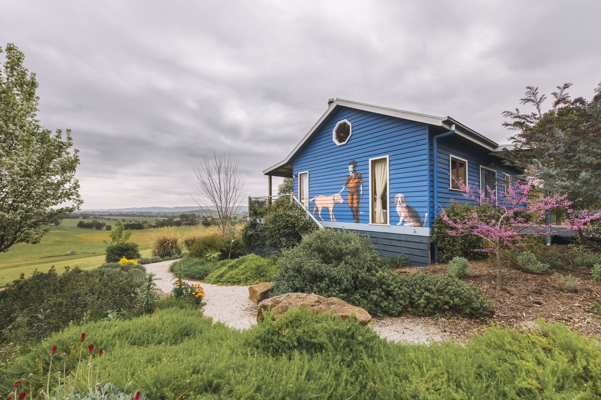 A blue house with a garden and a path leading to it.