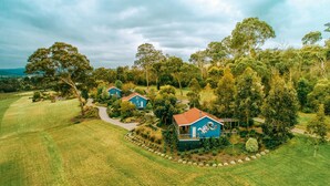 A rural property with two blue houses surrounded by lush greenery and a well-maintained lawn. - Outlook Hill Vineyard Cottages (Tarrawarra)