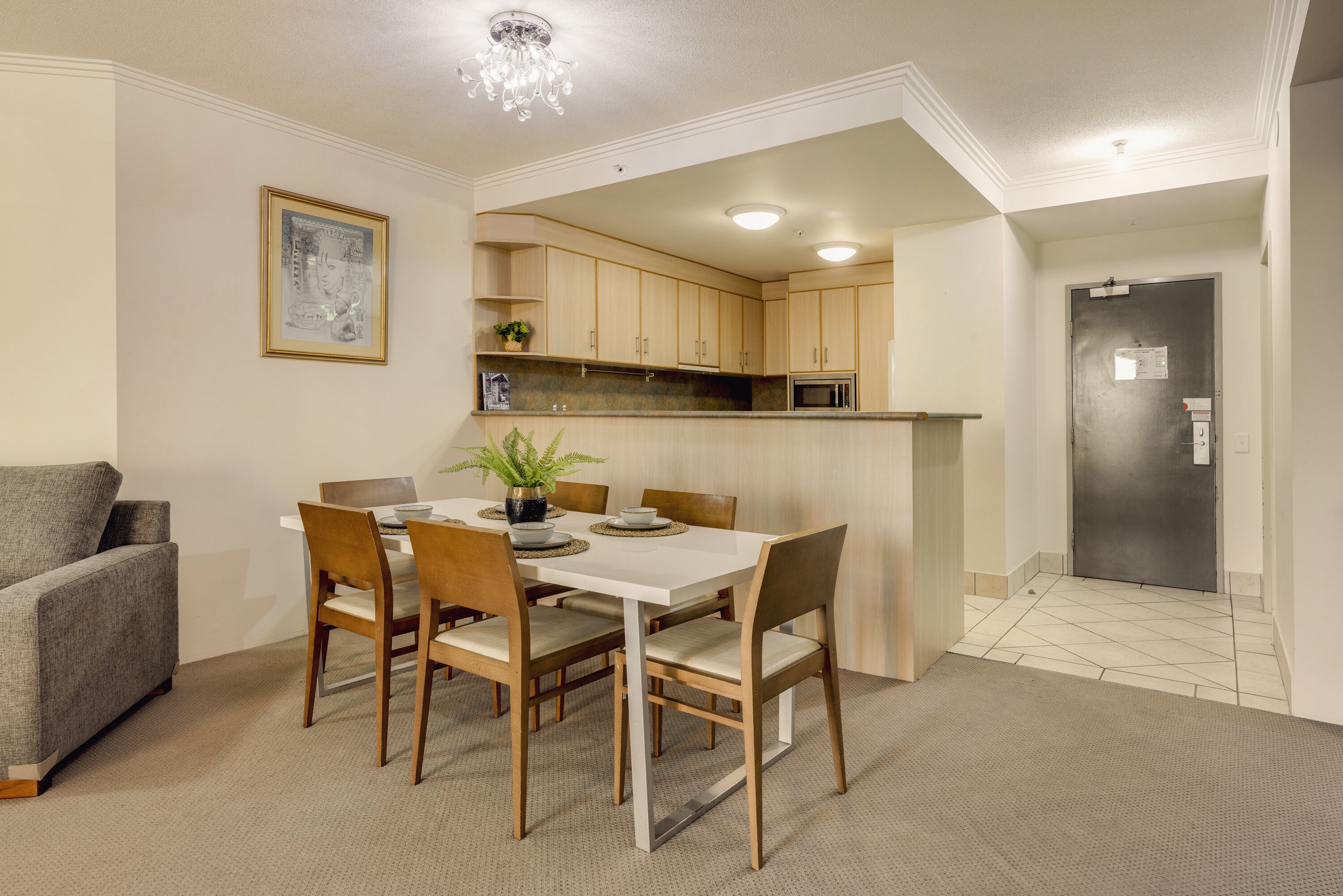 Una cocina moderna con armarios blancos, una mesa de comedor con sillas y un refrigerador.