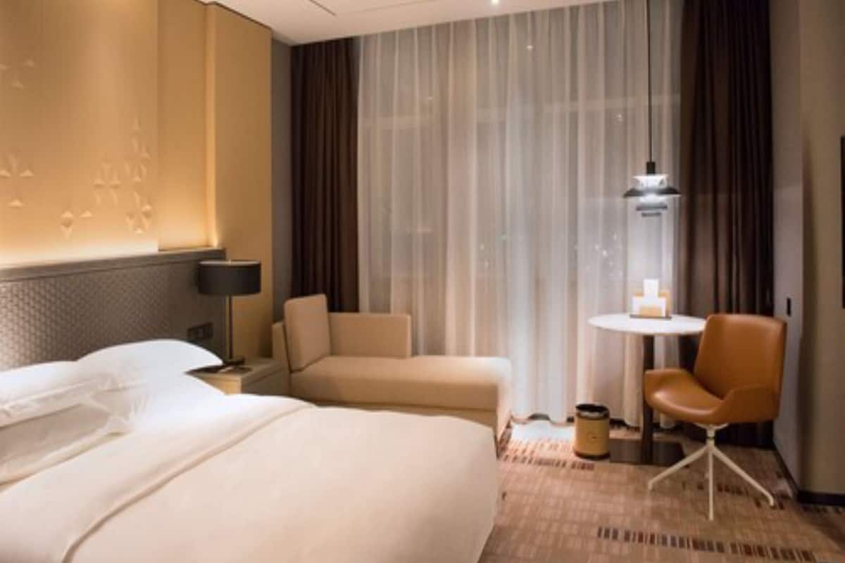 A hotel room with a large bed, a sofa, a small table with a candle, and a chair.