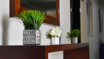 A reception desk with a mirror, a potted plant, and a vase with flowers.