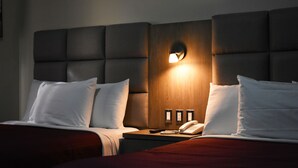 A hotel room with a large bed, a bedside table with a lamp, and a phone. - Hotel Jatay (Tijuana)