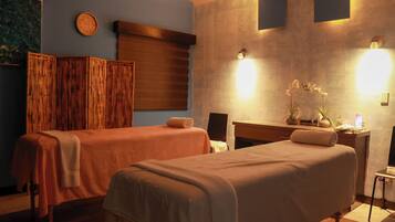 Two beds, a desk, and a chair are featured in this room, along with a clock and wall-mounted lights.