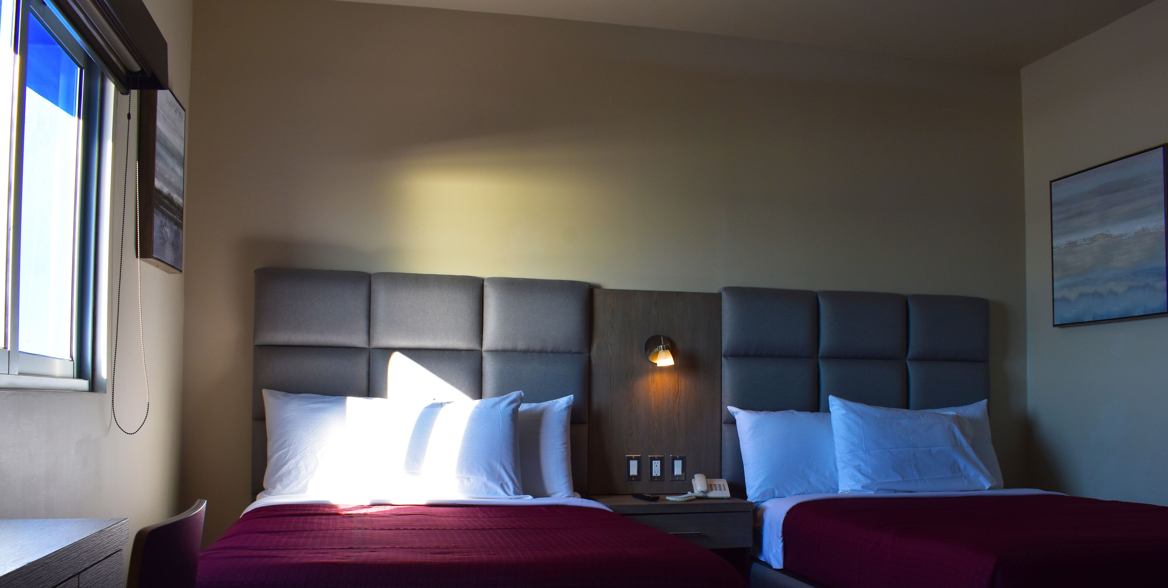 Une chambre d’hôtel avec deux lits, un bureau et une fenêtre.