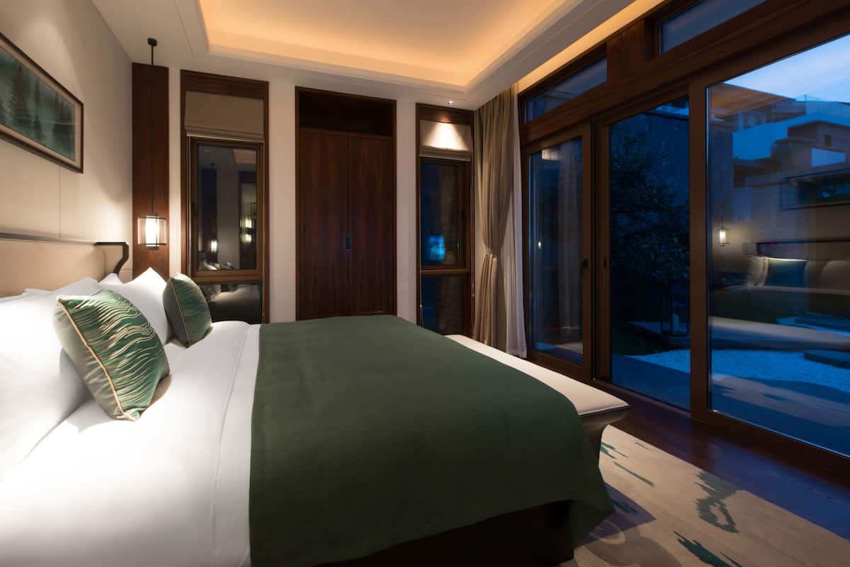 Une chambre d’hôtel moderne avec un grand lit, une vue sur l’extérieur et une porte-fenêtre coulissante.