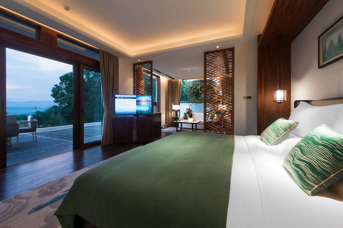 Une chambre d’hôtel moderne dotée d’un grand lit, d’une télévision et d’un balcon offrant une vue panoramique.
