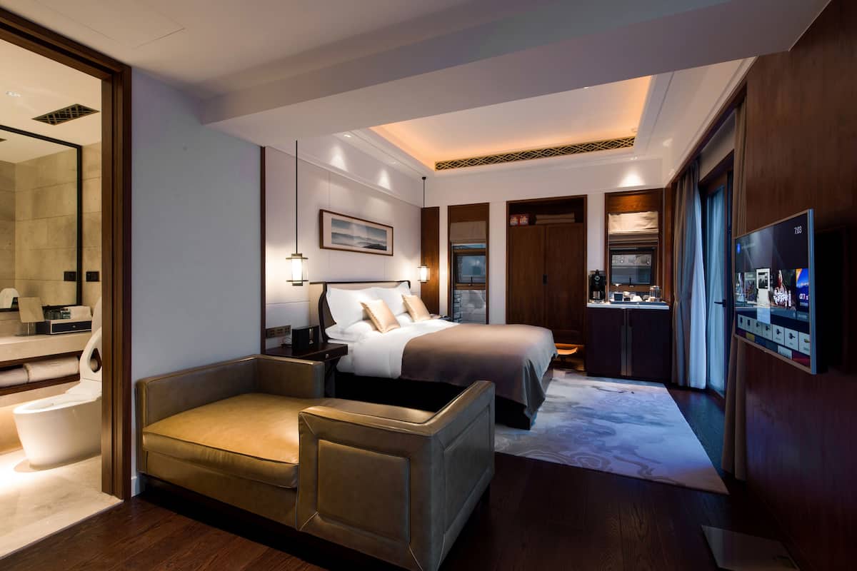 Une chambre d’hôtel moderne équipée d’un lit, d’un canapé, d’un bureau, d’une télévision et d’une salle de bain.