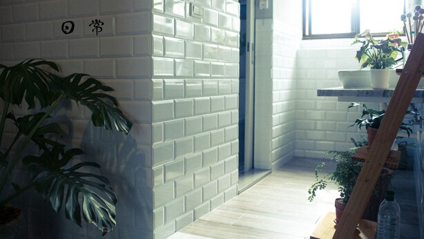 A modern kitchen with white subway tiles, a wooden floor, and a large potted plant. - Civil Life Guesthouse Tainan (Tainan)