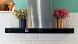 A kitchen with a stainless steel range hood, white tiled backsplash, and two flower vases on the range hood. - Civil Life Guesthouse Tainan (Tainan)