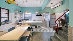 A modern kitchen with a central island, white cabinets, and a red staircase. - Civil Life Guesthouse Tainan (Tainan)