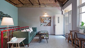 A cozy living room with a green sofa, a glass coffee table, and a red railing. - Civil Life Guesthouse Tainan (Tainan)